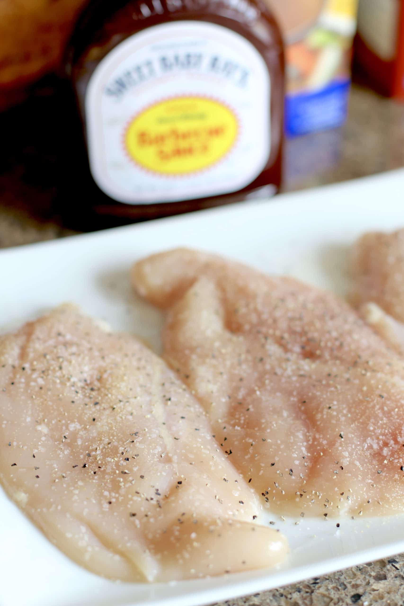 chicken breasts, seasoned with salt, pepper, and garlic powder, on a white plate.