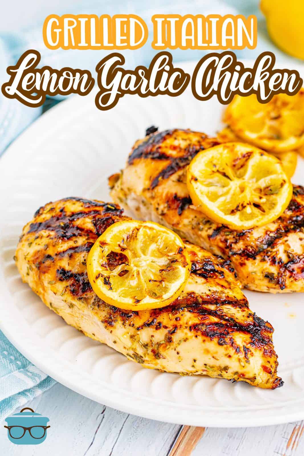Grilled Italian Lemon Garlic Chicken Bread recipe from the Country Cook. Photo showing two grilled chicken breasts with lemon slices on top on a white round plate.