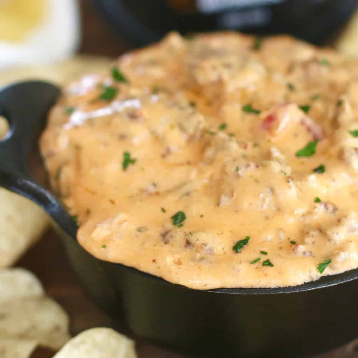 closeup photo of pimento cheese sausage dip in a small black cast iron container with handles.