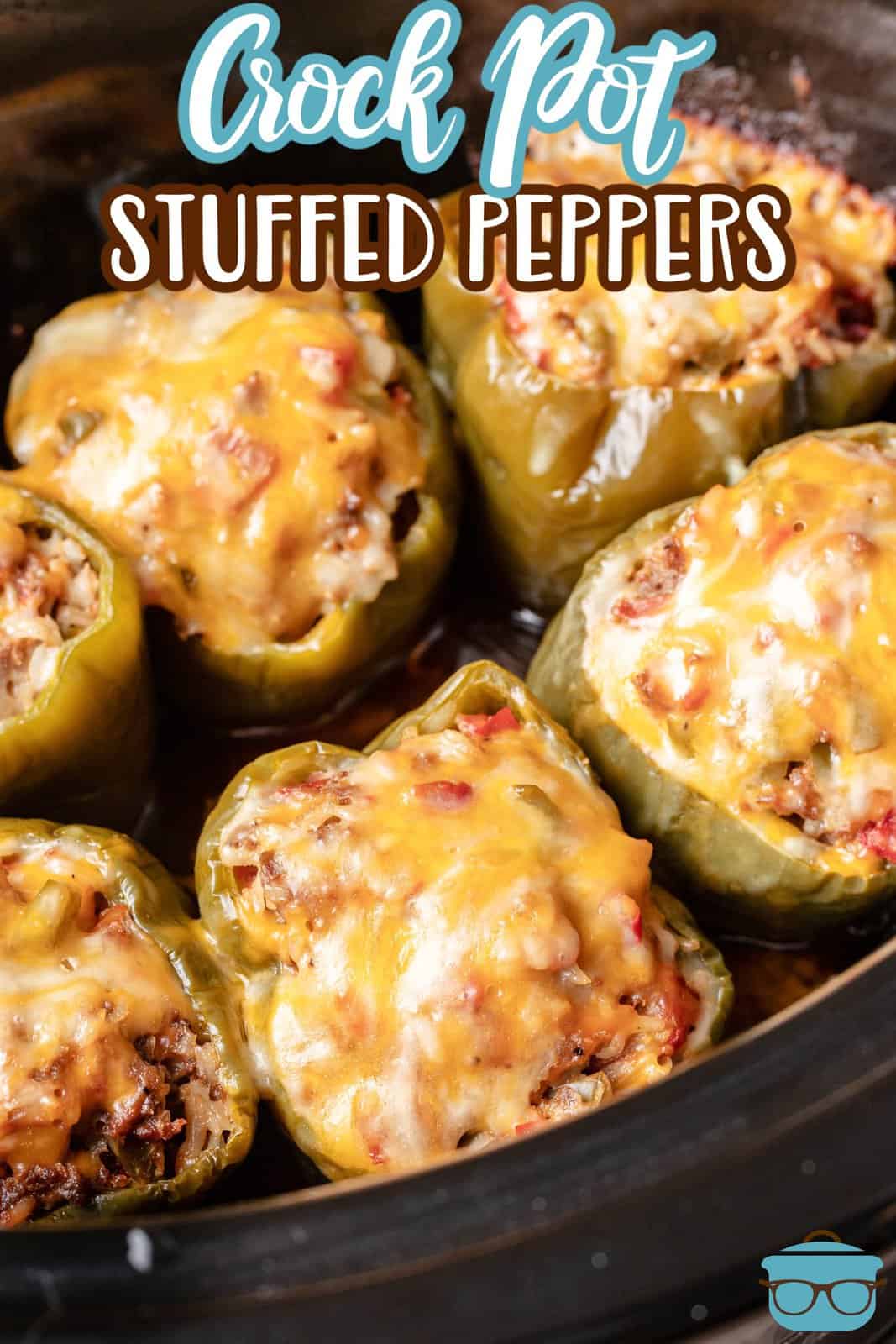 fully cooked stuffed peppers with melted cheese on top shown in an oval slow cooker. 
