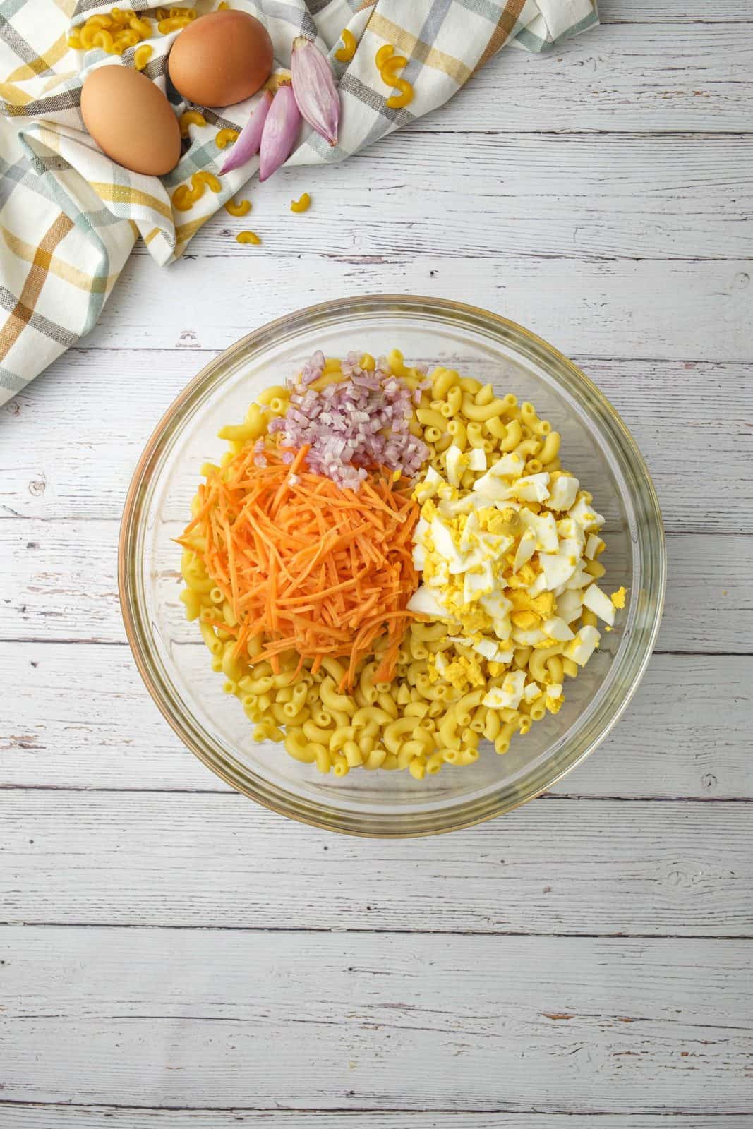 diced boiled eggs, shredded carrots and diced shallots added to bowl with cooked macaroni.