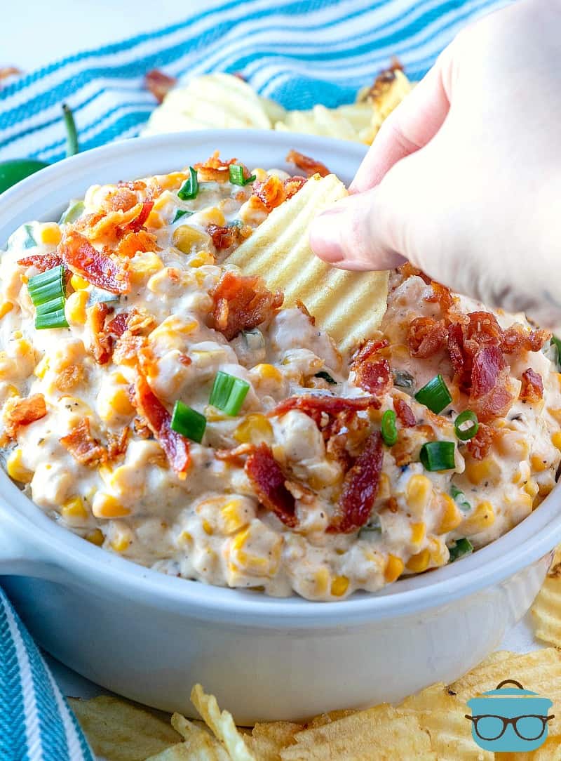 Jalapeno Popper Corn Dip served in a white serving bowl with a chip.