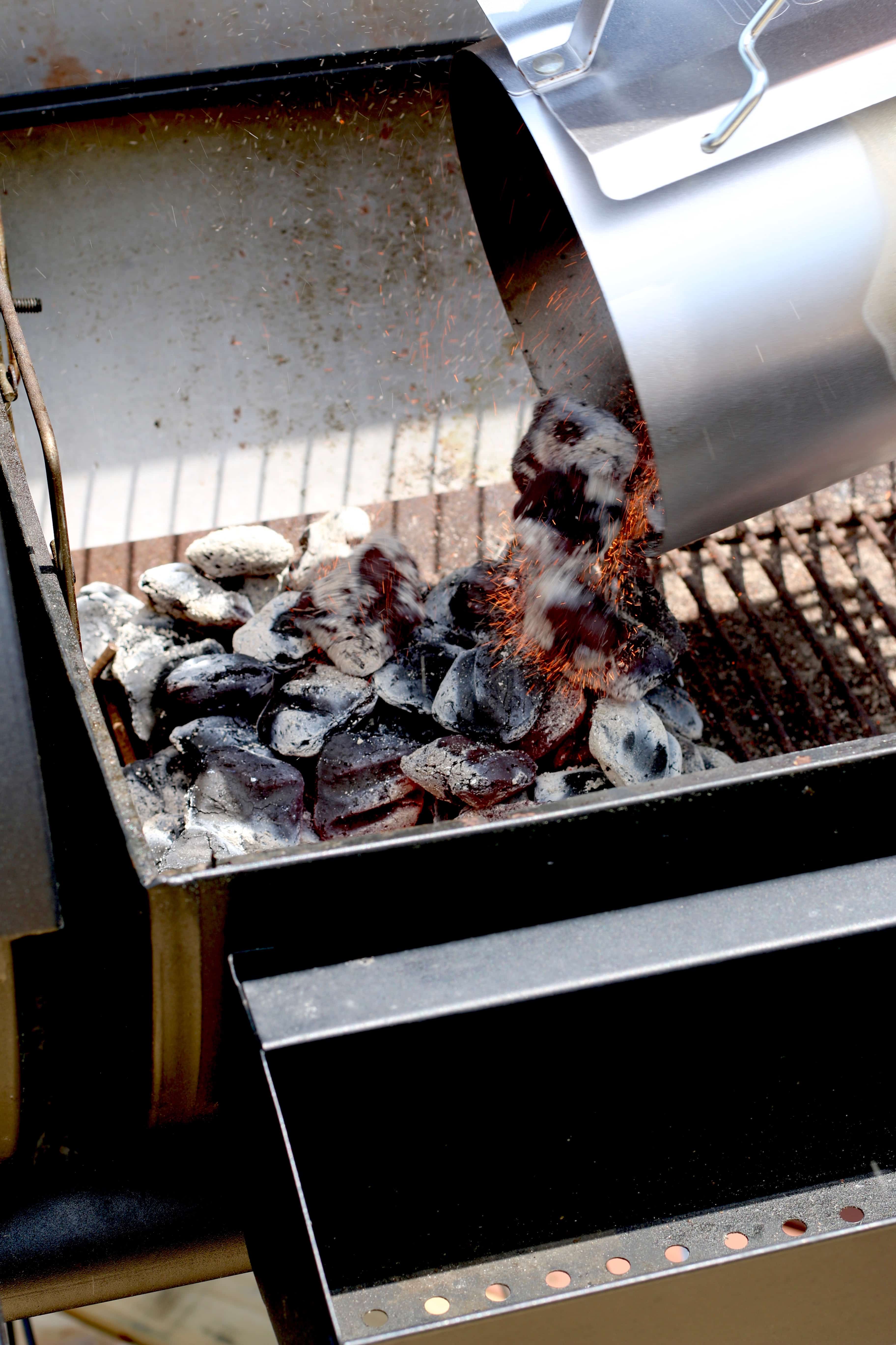 pouring charcoal briquets into the bottom of a charcoal grill.