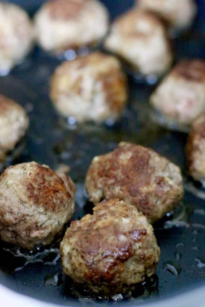 browning homemade meatballs in a large pan
