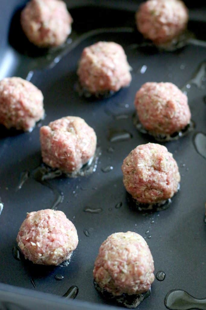meatballs cooking in a large skillet with a little bit of olive oil