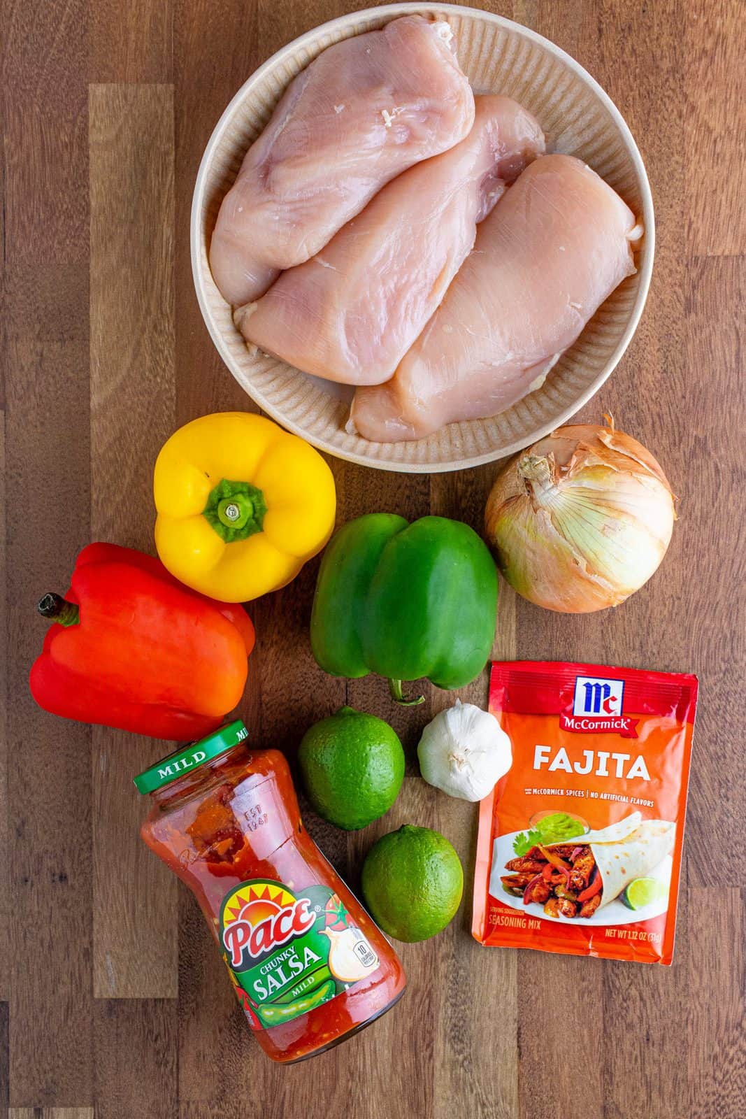 Ingredients needed to make chicken fajitas: red, yellow, green bell peppers, onion, garlic, salsa, boneless, skinless chicken breasts, fajita seasoning, fresh lime juice