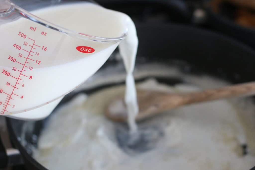pouring milk into skillet into roux
