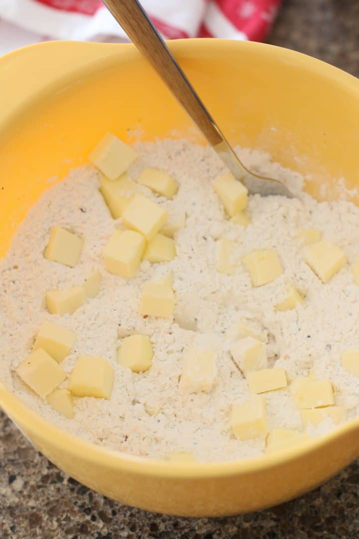 flour and cubed butter with a fork in a yellow mixing bowl