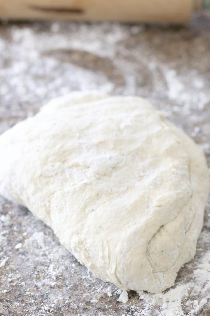 Pizza dough being kneaded on a floured surface. 