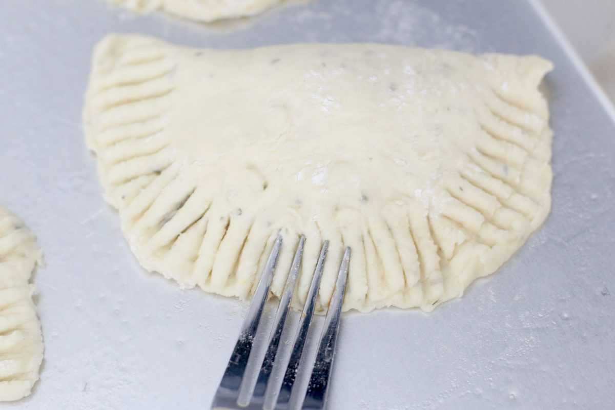 A fork crimping the edges of the pizza pocket.