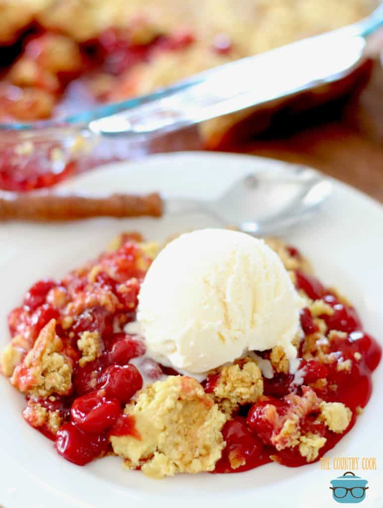 Cherry Dump Cake served on a white plate topped with vanilla ice cream and a spoon