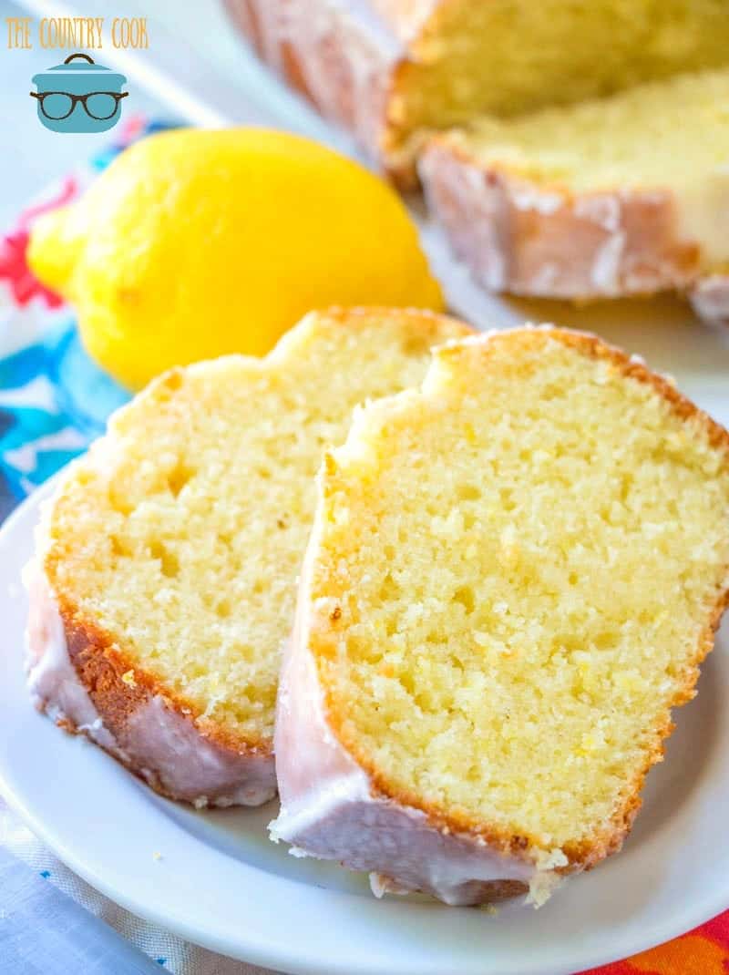 two lemon loaf slices on a white plate with a lemon in the background.