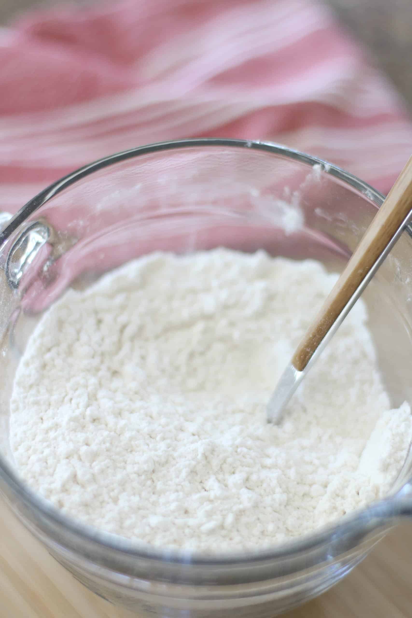 flour, salt and baking soda stirred together with a bowl in a large clear bowl.