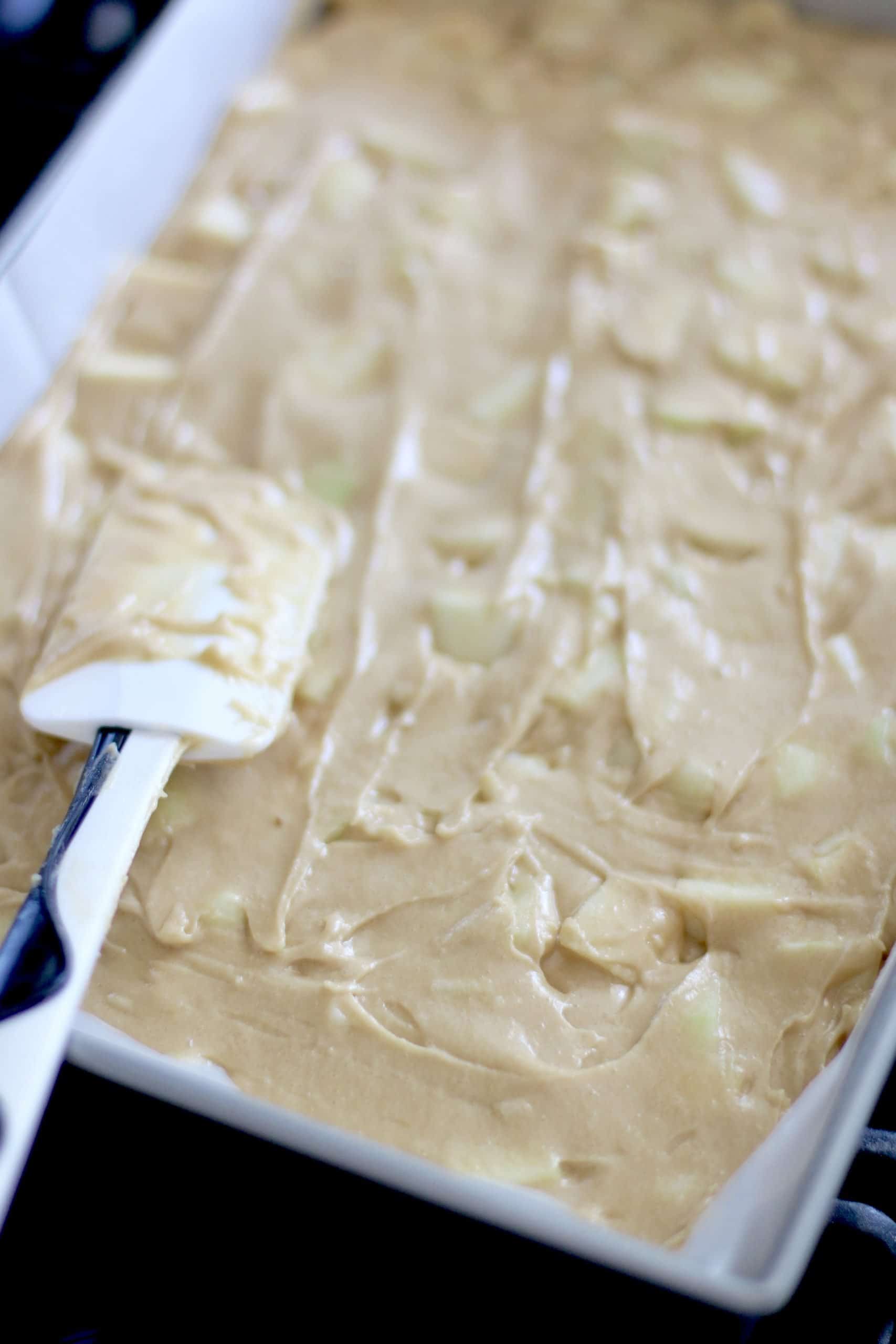 apple blondie batter spread into rectangle baking pan spread by a spatula.