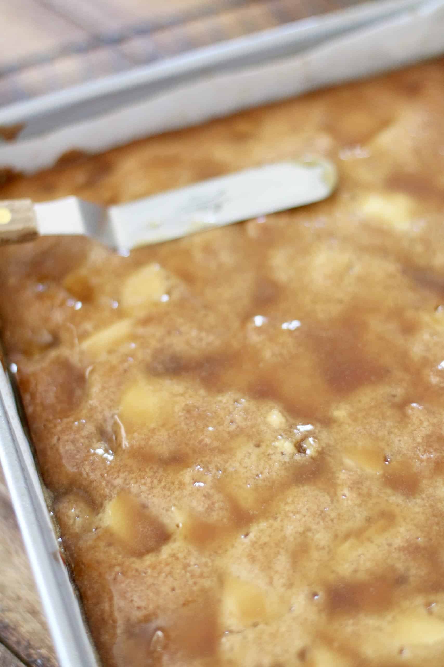 spreading maple glaze over apple blondies with an offset spreader.