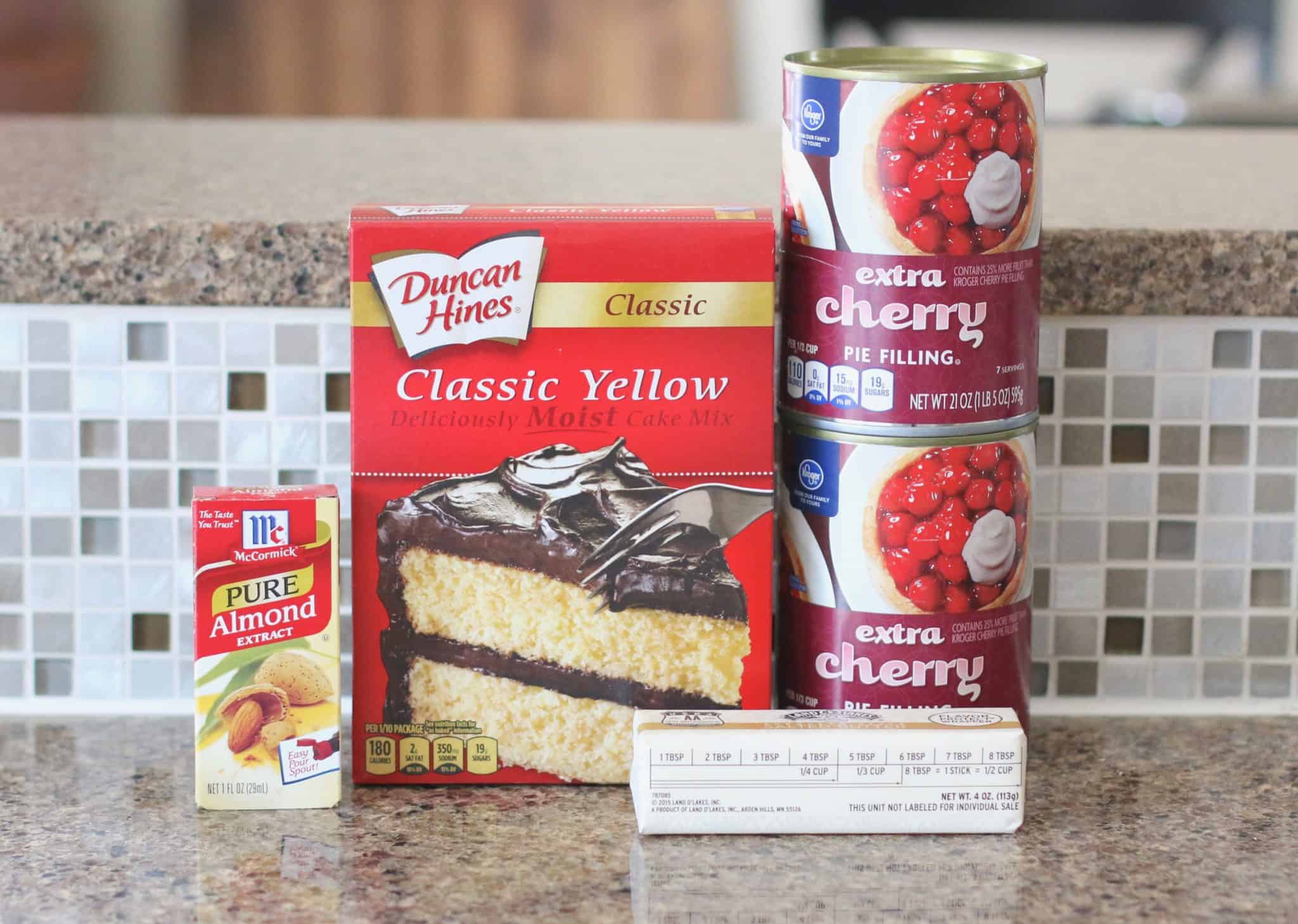 ingredients for cherry dump cake: yellow boxed cake mix, two cans cherry pie filling, salted butter, almond extract