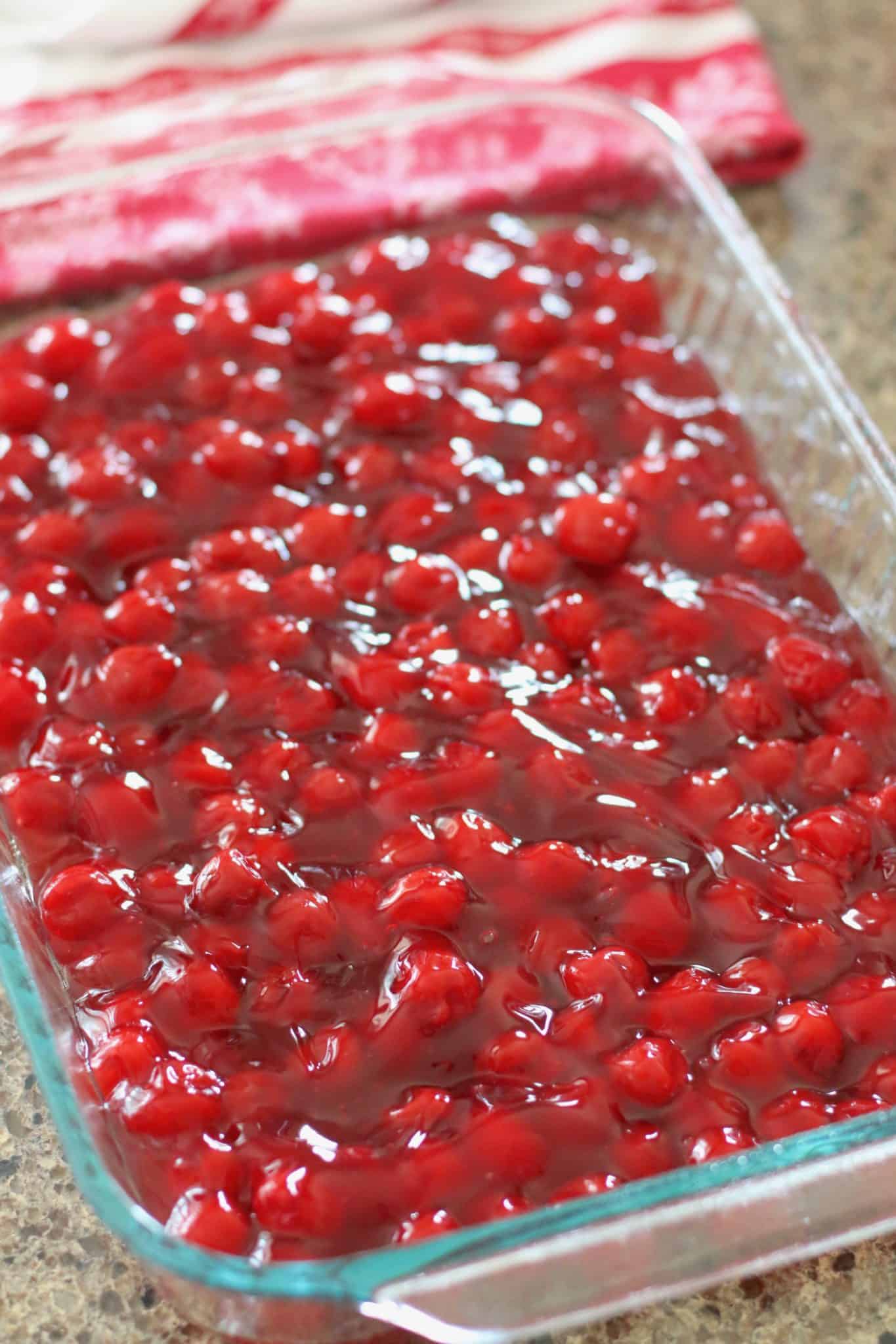 cherry pie filling poured into a Pyrex glassware baking dish