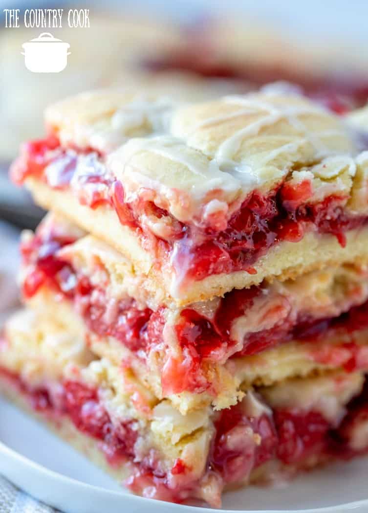 cherry pie bars, shown close up, three cherry bars stacked on top of each other on a white plate.
