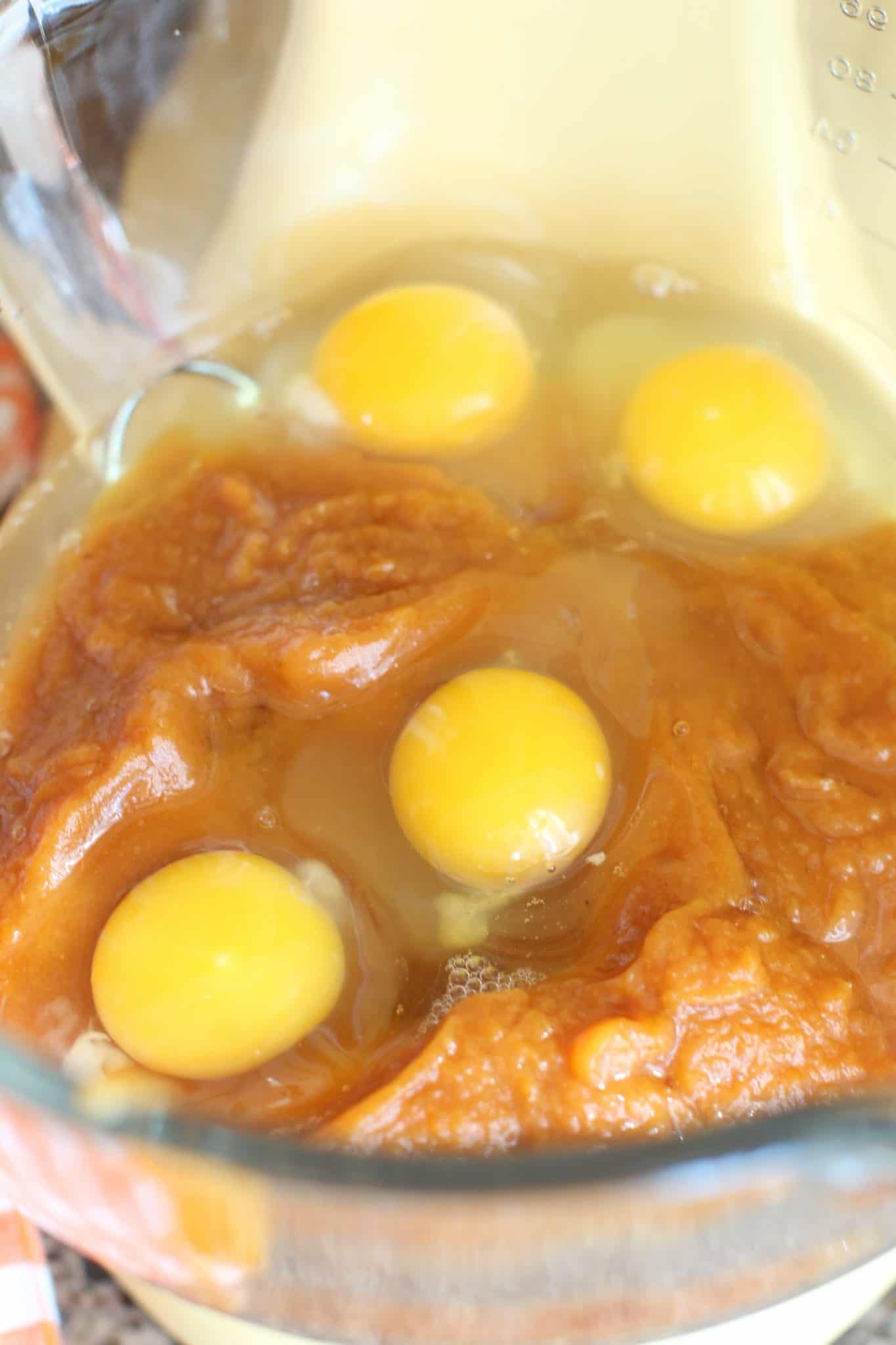 four eggs added to pumpkin pie filling in a glass mixing bowl