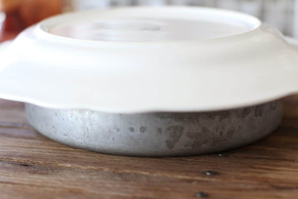 white plate placed on top of a silver round baking dish