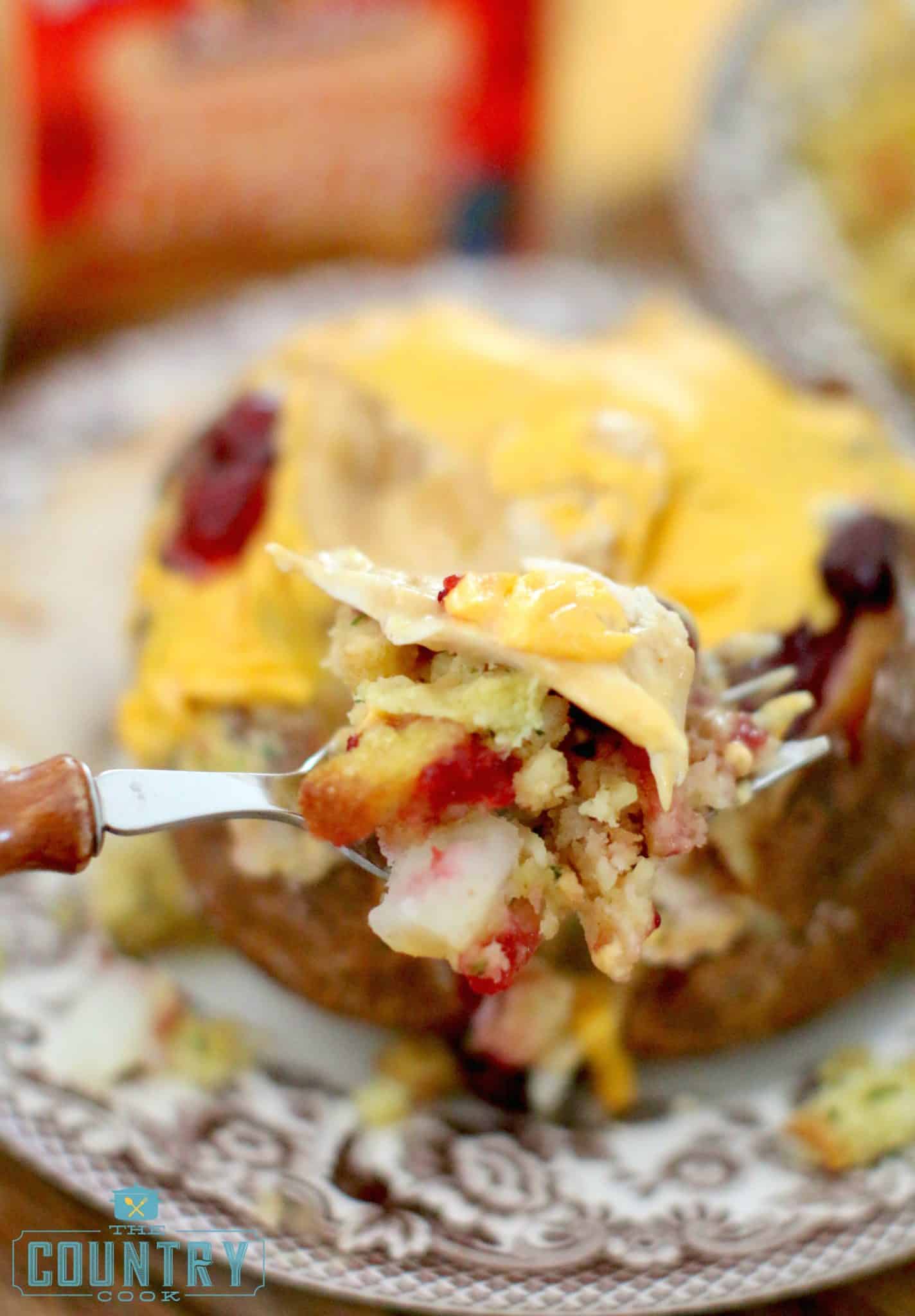 A fork holding a serving of baked potato with turkey and stuffing.