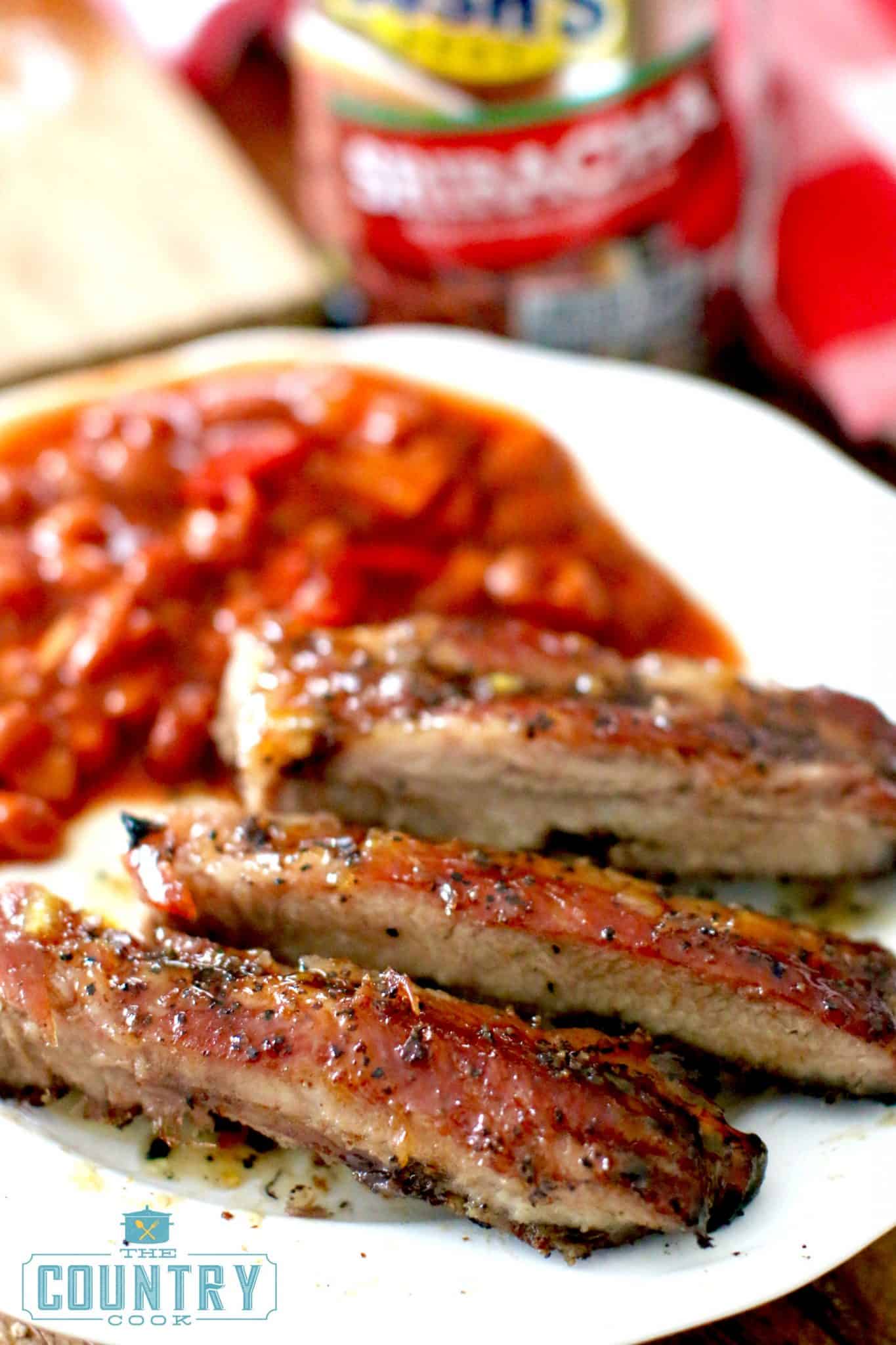 fully cooked rib slices on a plate served with baked beans.