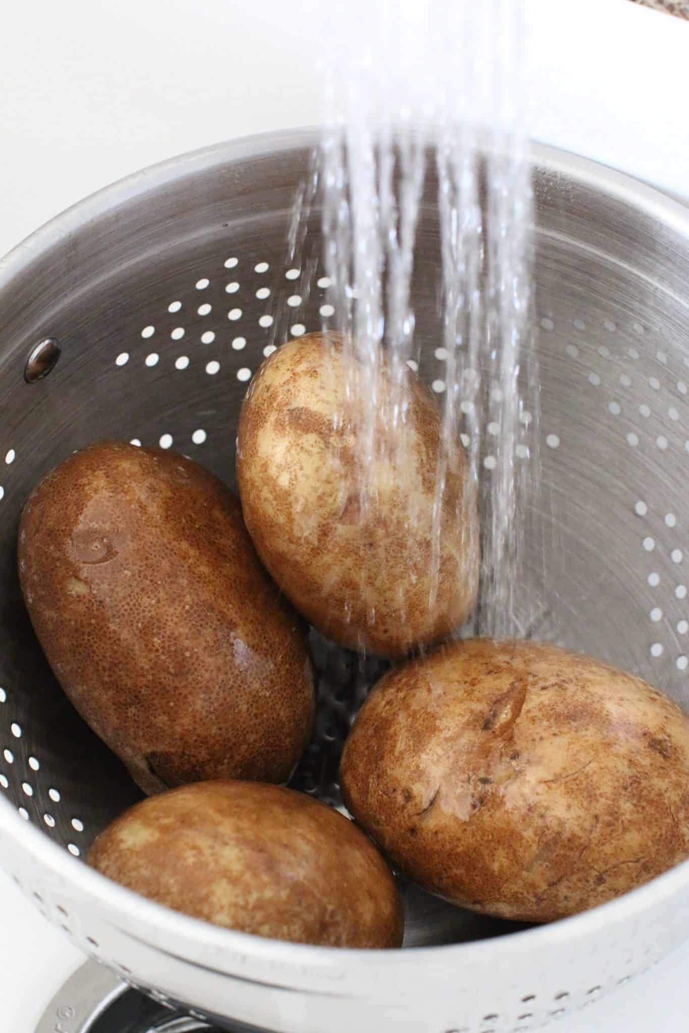 rinsing russet potatoes in a colander.