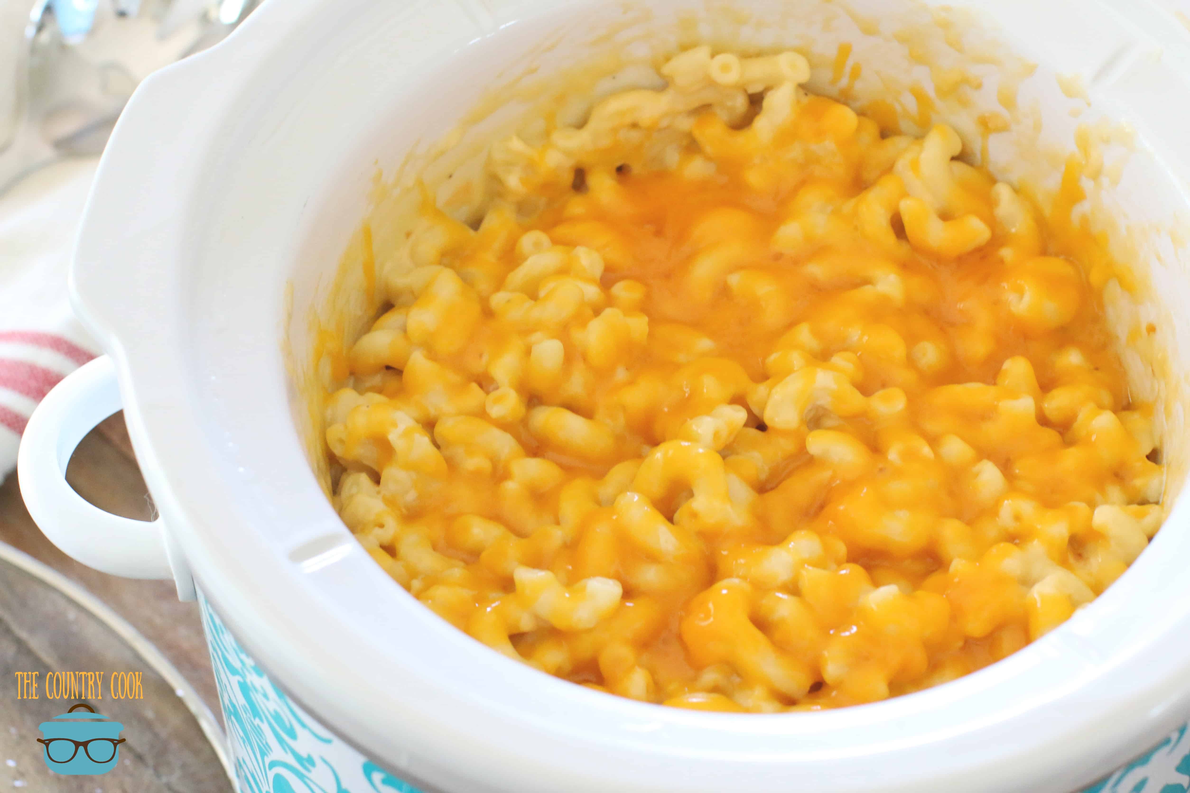 melted cheese on macaroni and cheese shown in a round slow cooker.