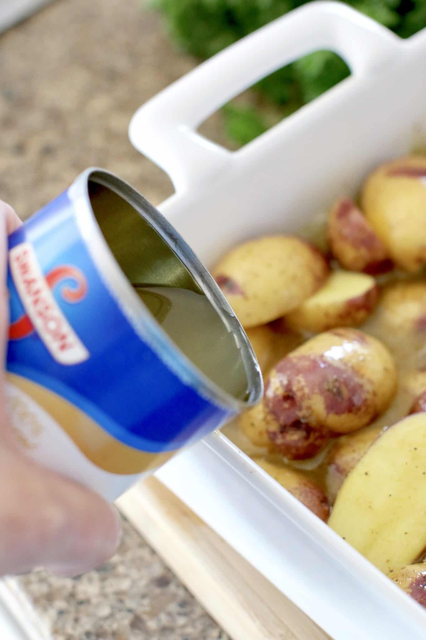 a can of chicken broth shown pouring into sliced potatoes in baking dish. 