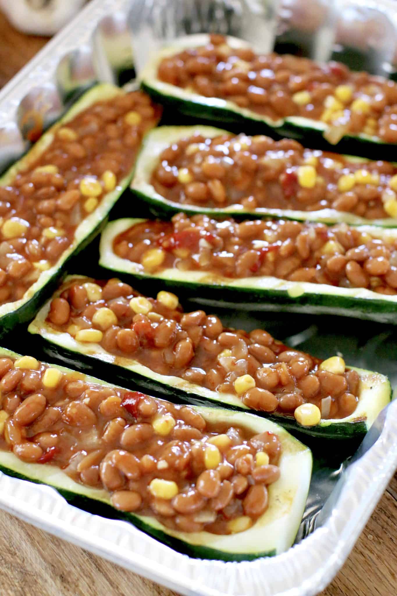 zucchini halves filled with bean mixture and placed into an aluminum  baking dish.
