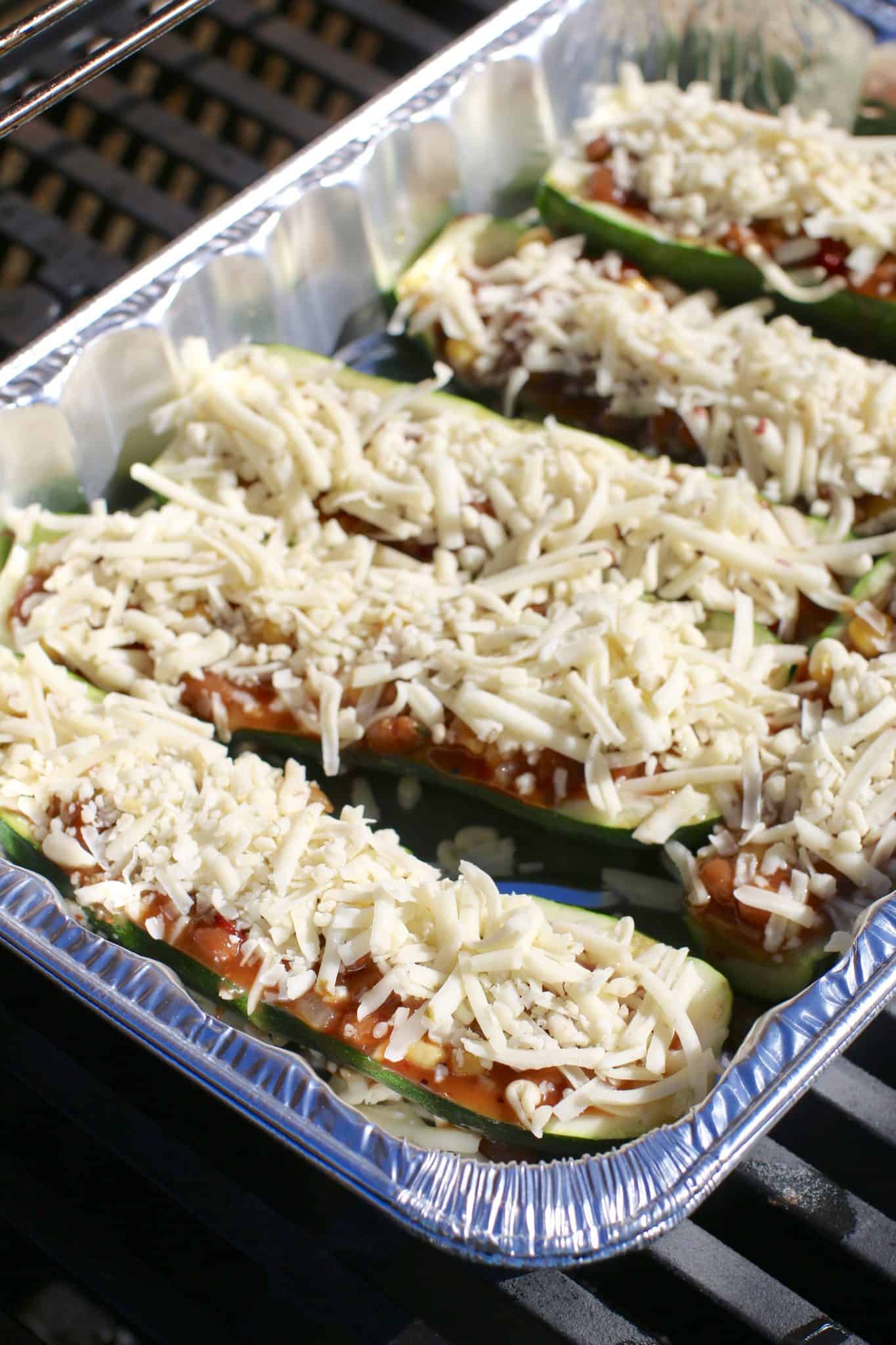 zucchini halves shown in an aluminum baking dish on the grill.