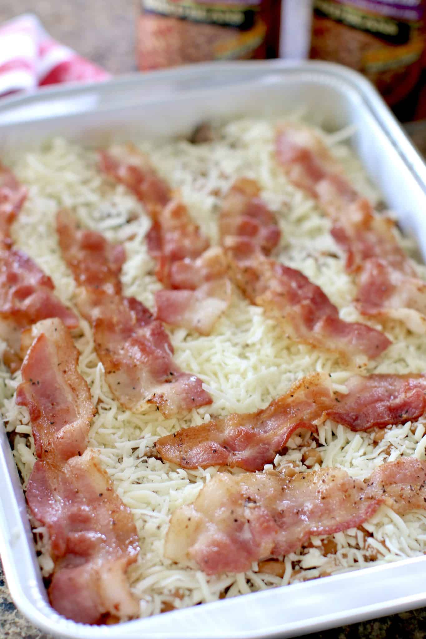 slices of bacon layered on the cheese in baking dish. 