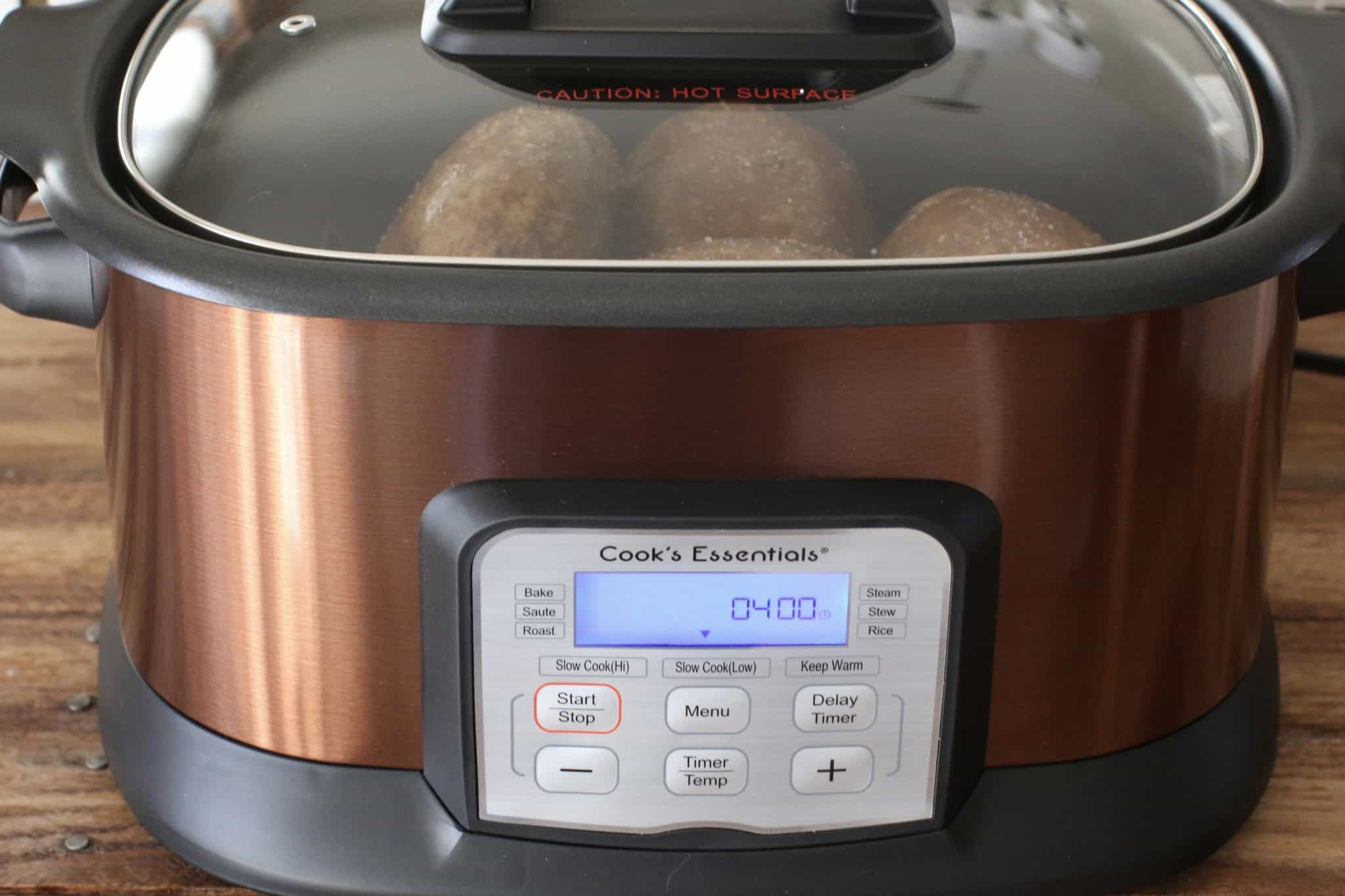 potatoes baking in a digital crock pot with lid on.