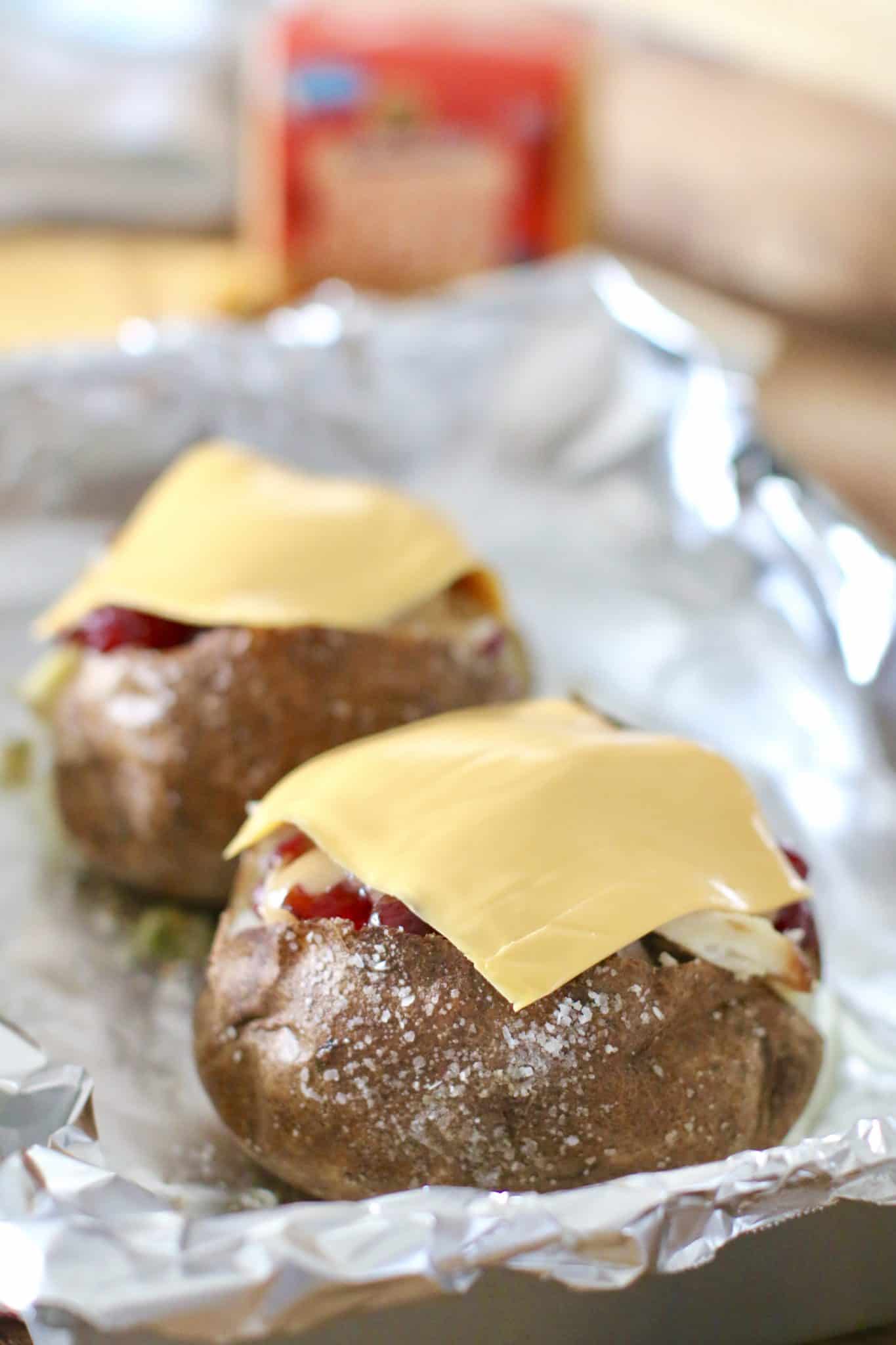 sliced cheese on top of stuffed baked potatoes.