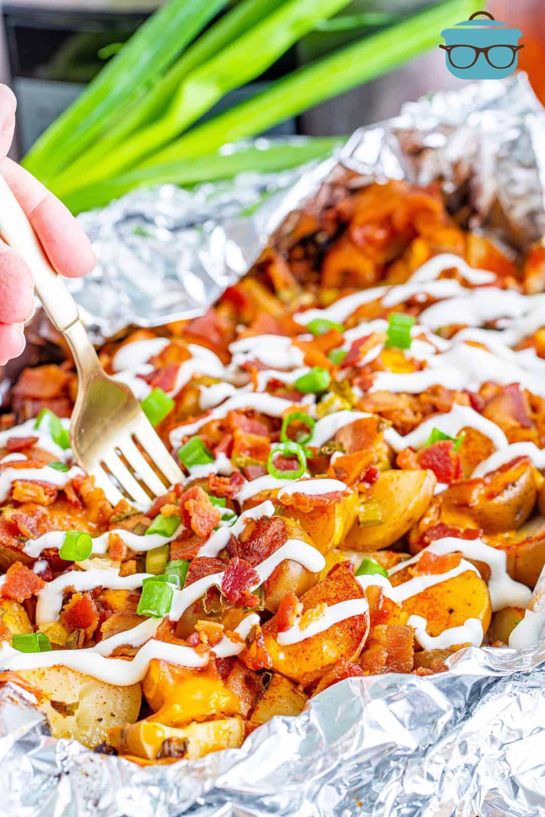 loaded potatoes in aluminum foil with a fork inserted. 