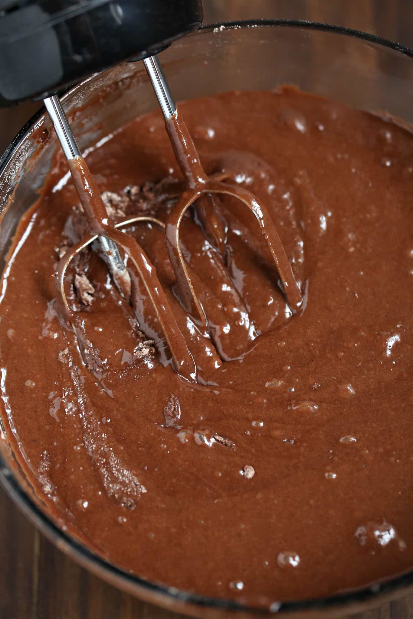 brownie batter shown in a clear bowl with mixing beaters.