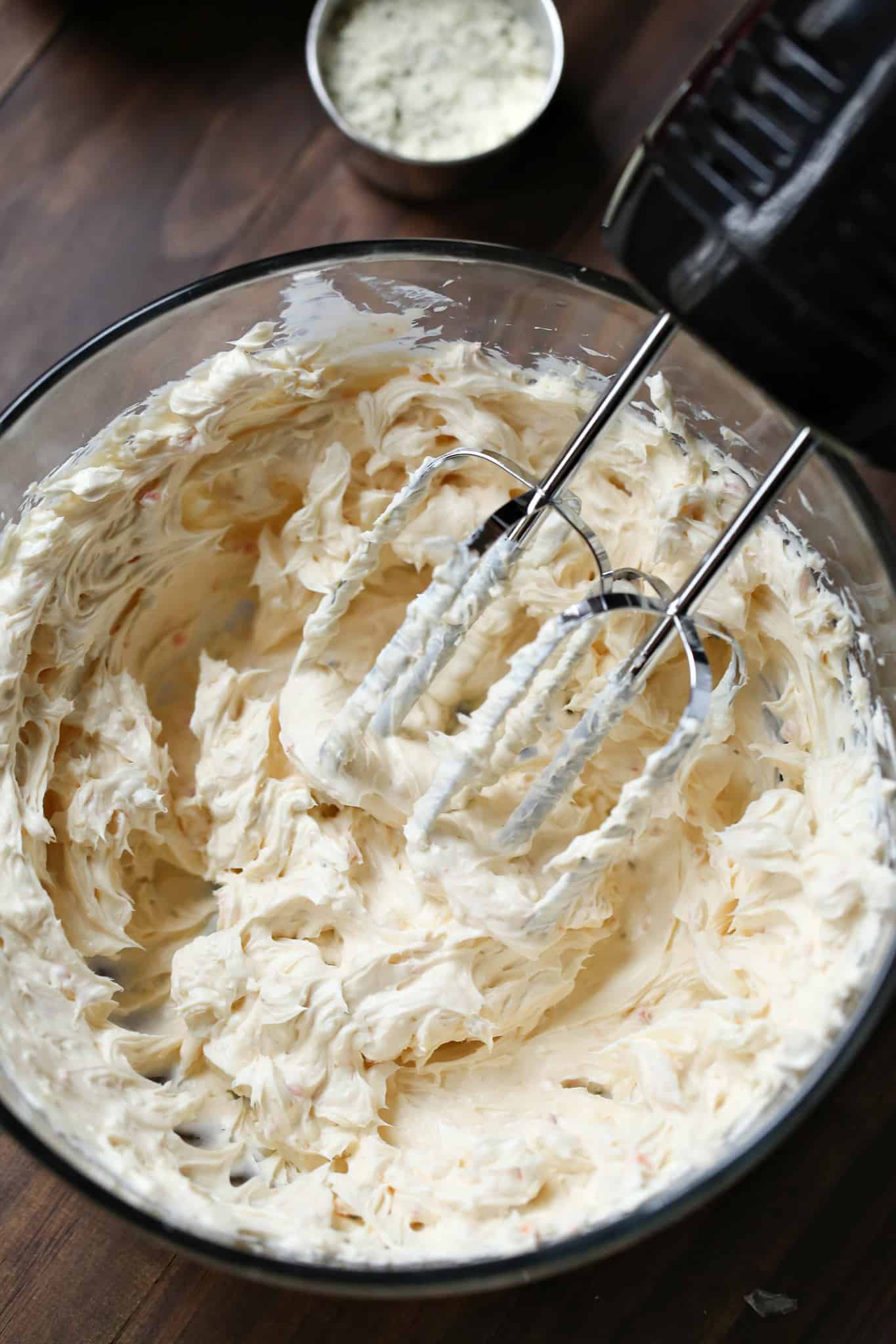 mixing cream cheeses together in al large bowl with a hand mixer.