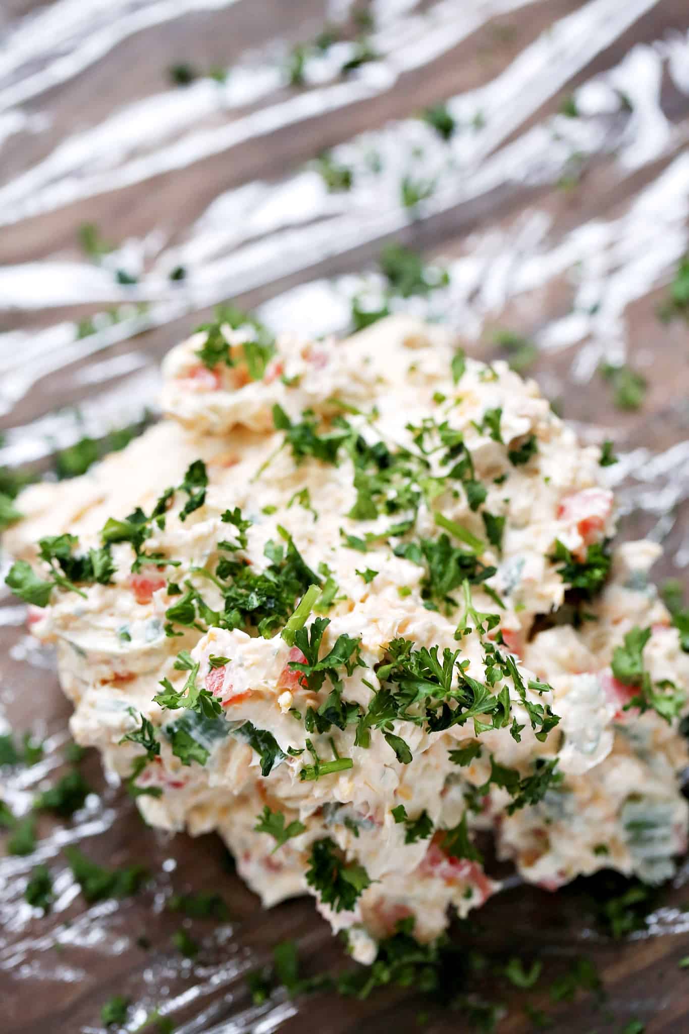 chopped parsley sprinkled on top of cream cheese mixture on plastic wrap.