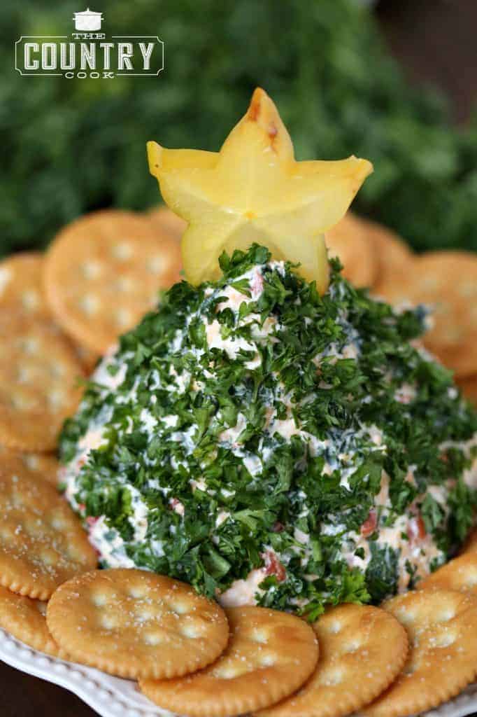 cheeseball shaped into a Christmas Tree covered in parsley and top with a star shaped fruit. 