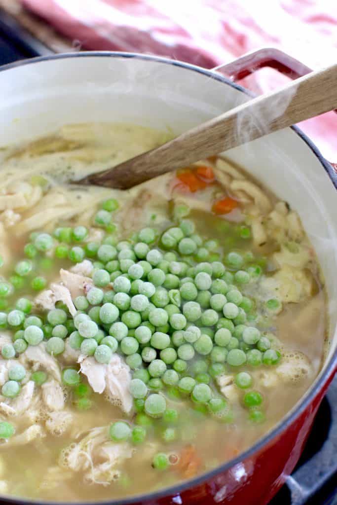 frozen peas added to chicken stew in pot.