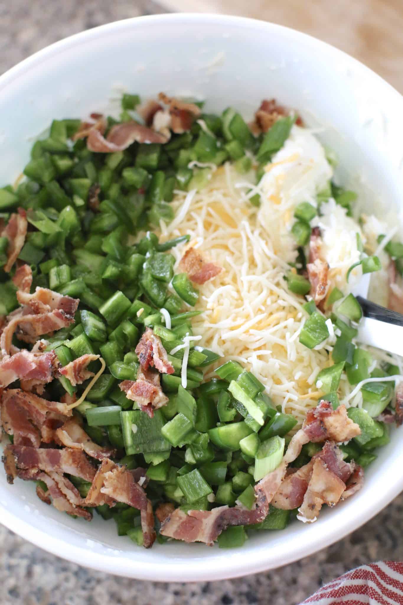cream cheese, sour cream, bacon and shredded cheese in a bowl.