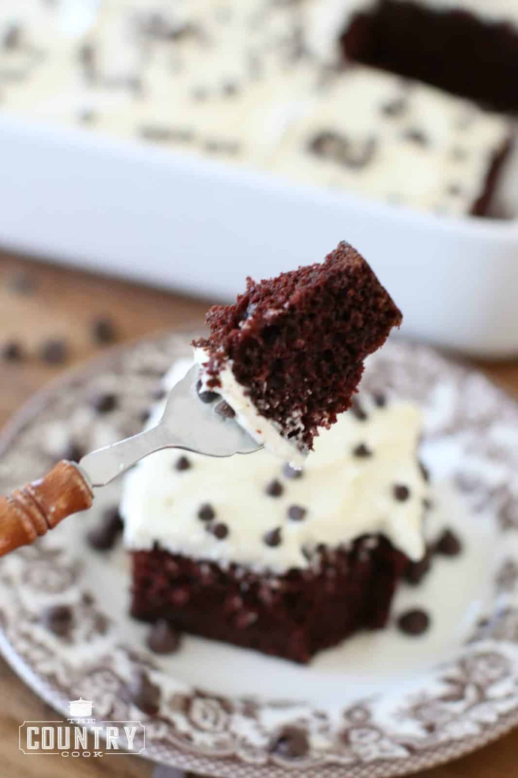 a small fork holding up a piece of chocolate cake.