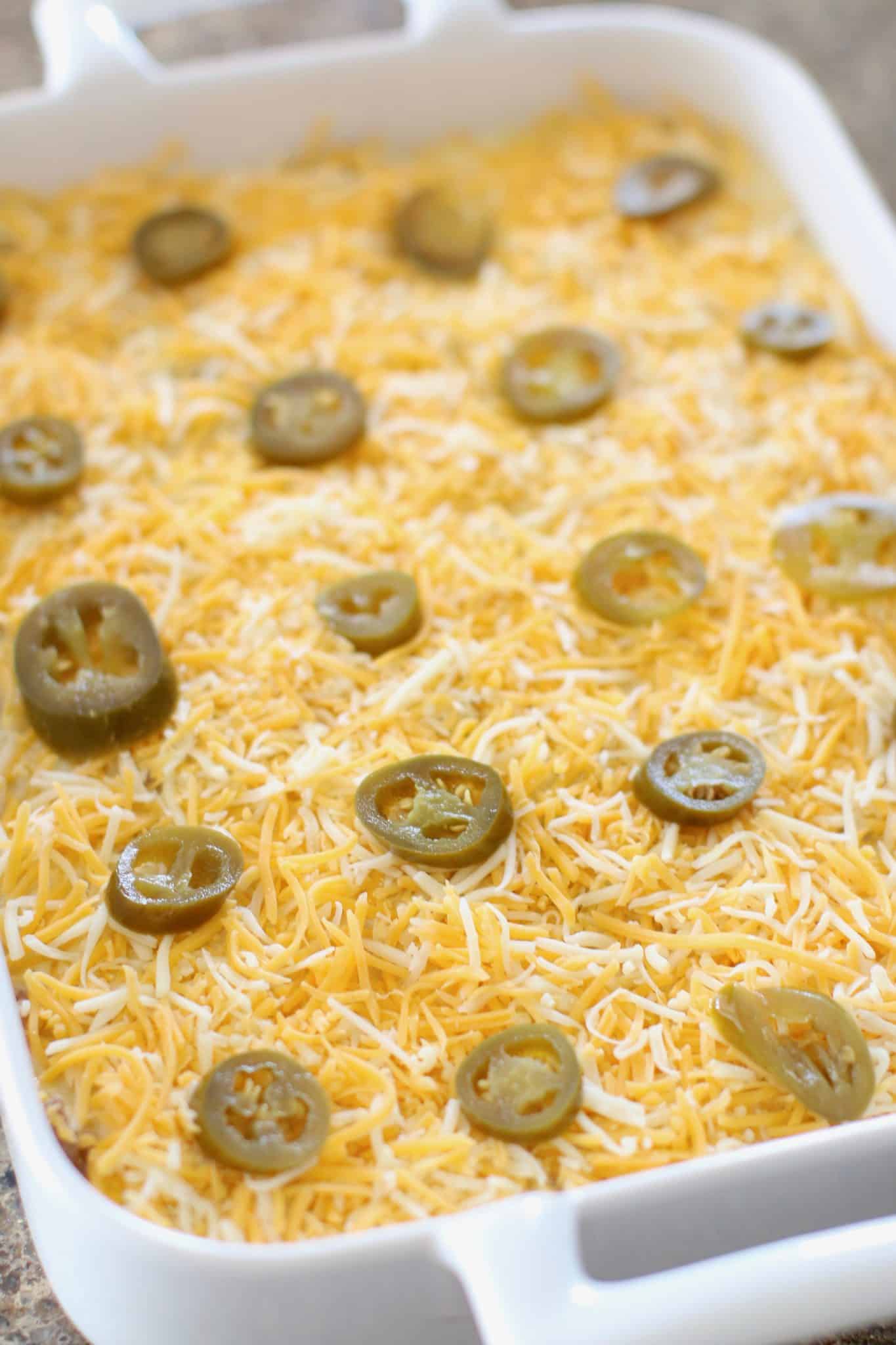shredded cheese layered on top of casserole mixture and topped with slices of jalapeños.