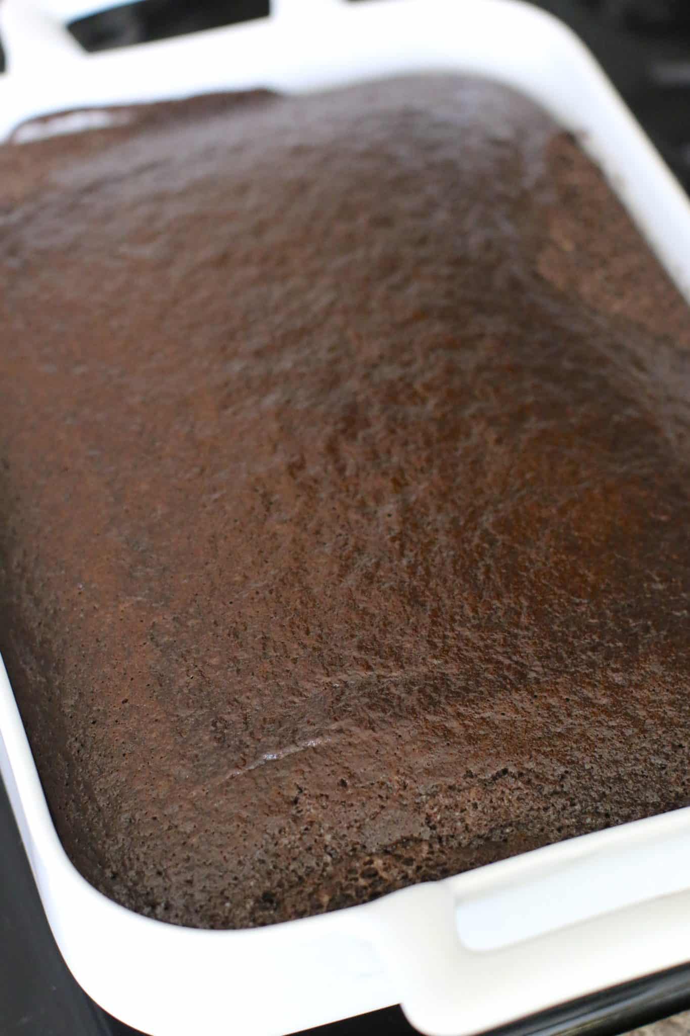 fully baked chocolate cake shown in a white rectangle baking dish with handles.