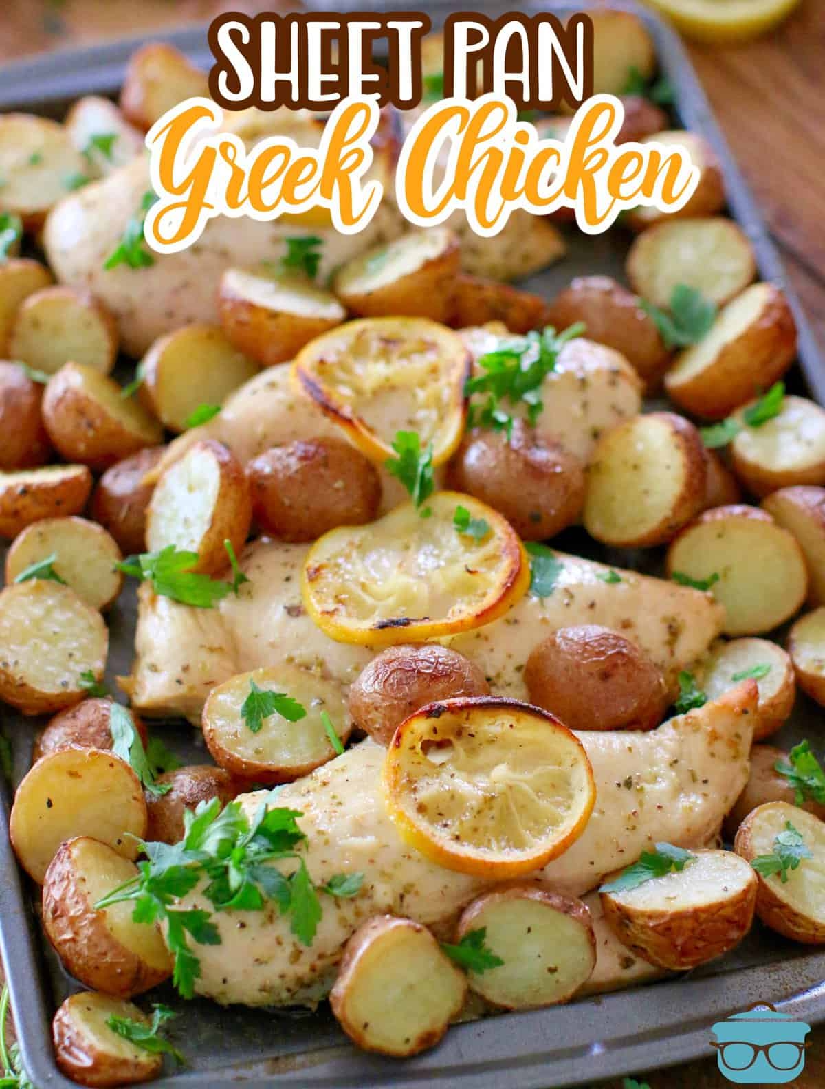 a sheet pan with cooked Greek chicken topped with lemon slices and cooked slice potatoes. 
