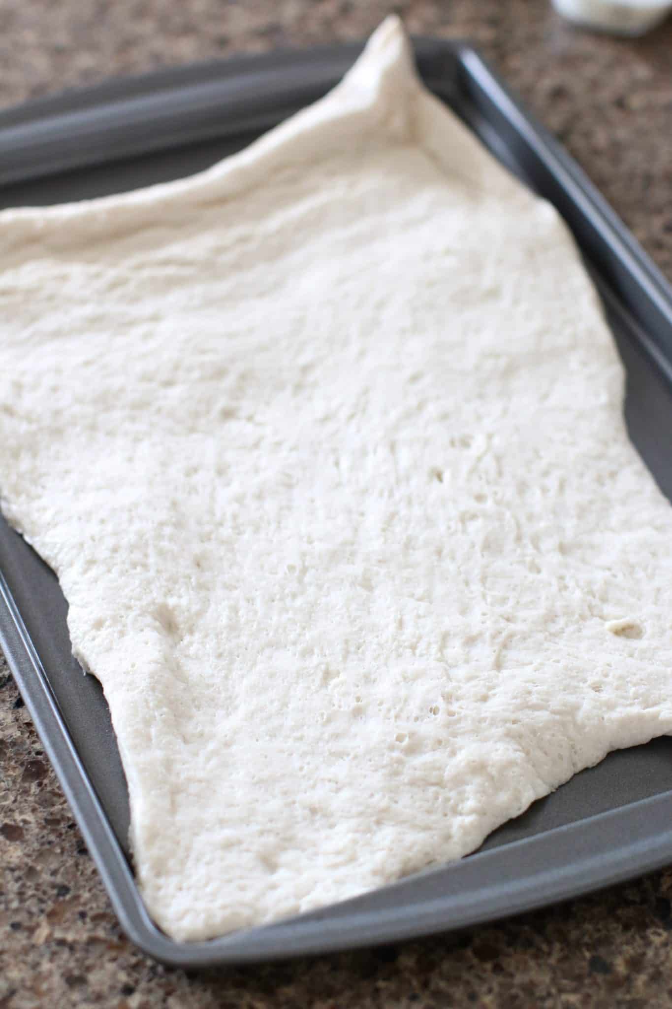 pizza dough shown on a baking sheet