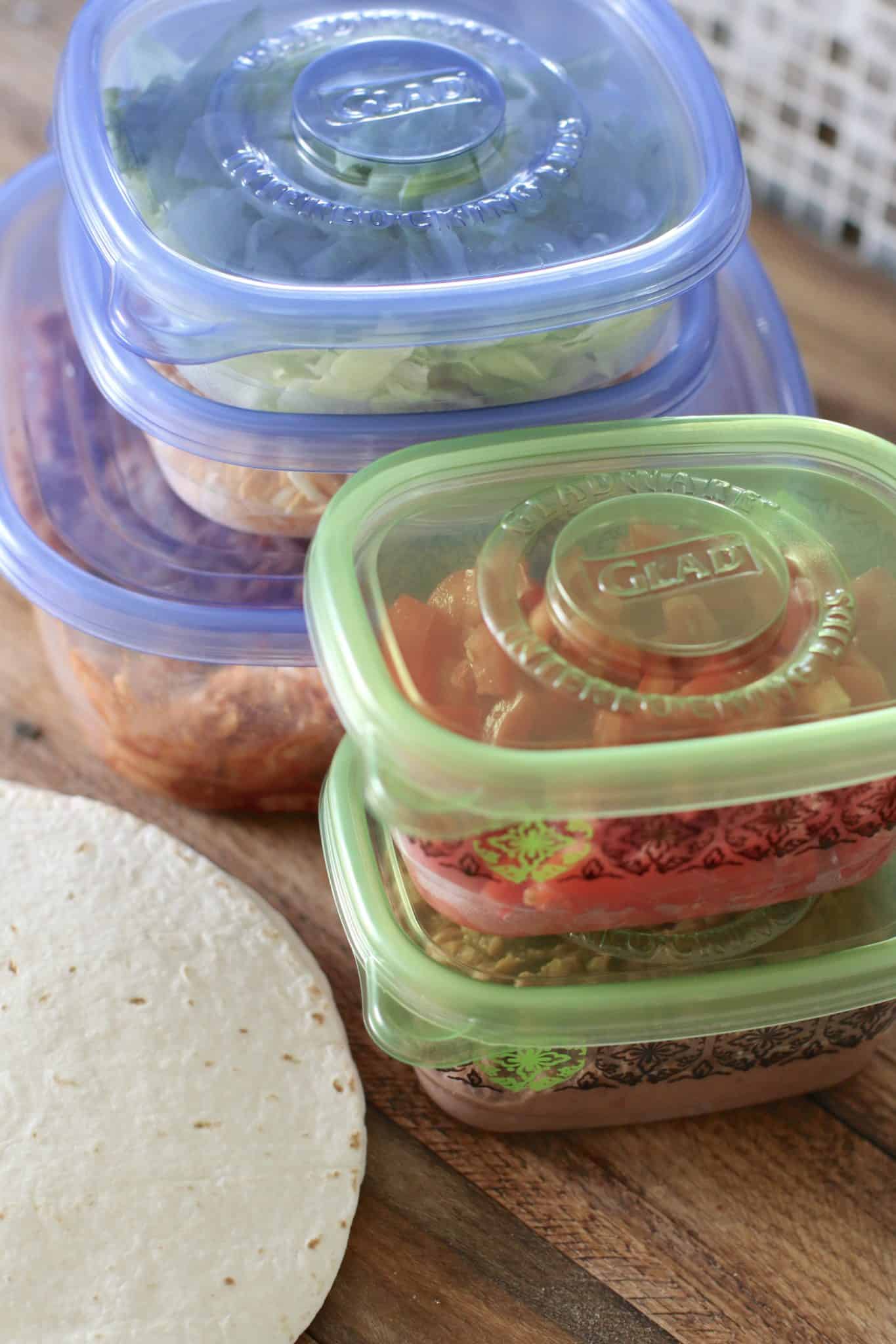 five plastic containers that contain various taco toppings