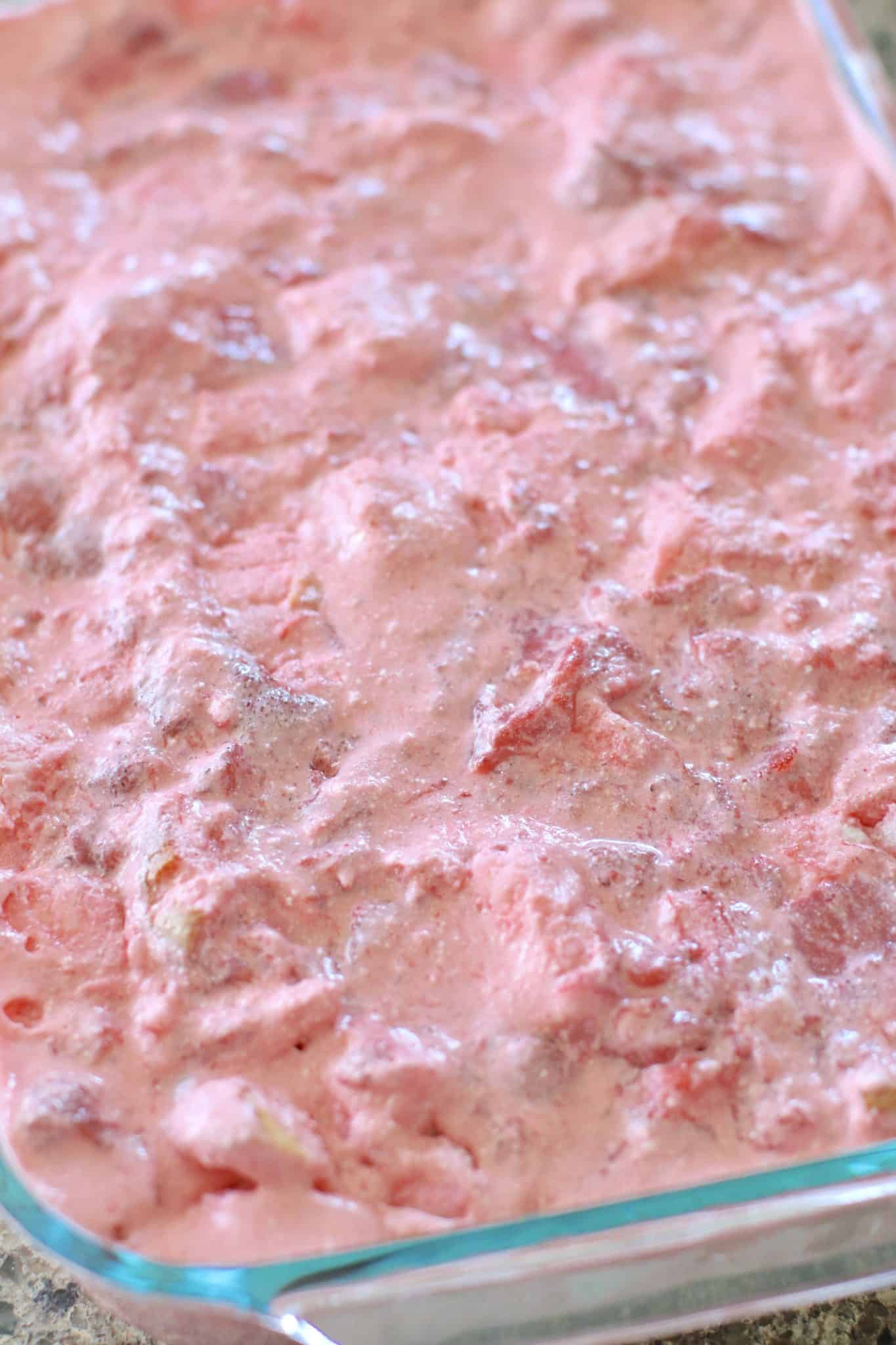 final layer of strawberry gelatin mix spread out on. top of diced angle food cake.