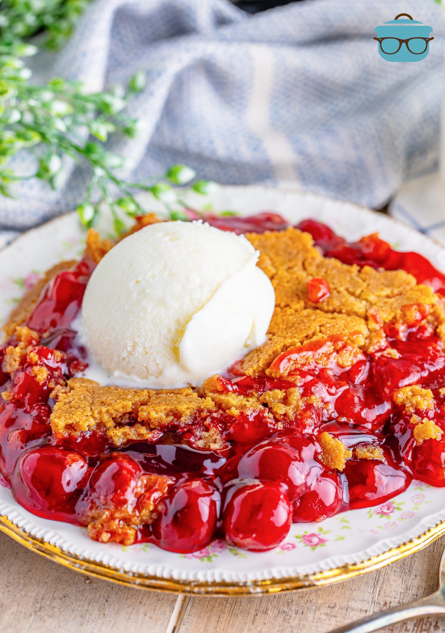A plate with a large serving of Jiffy Cherry Cobbler and a scoop of ice cream.