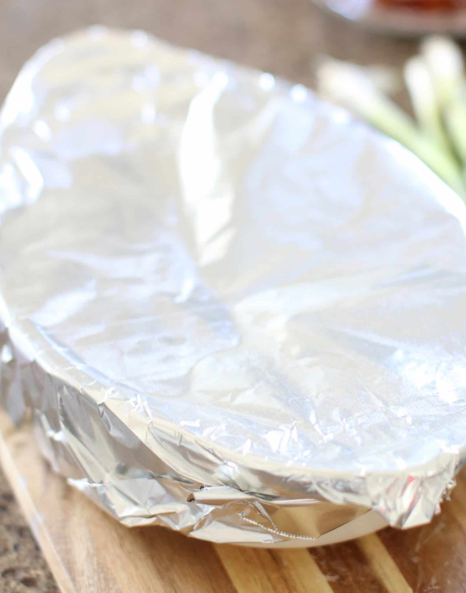 white oval baking dish shown covered with nonstick aluminum foil.